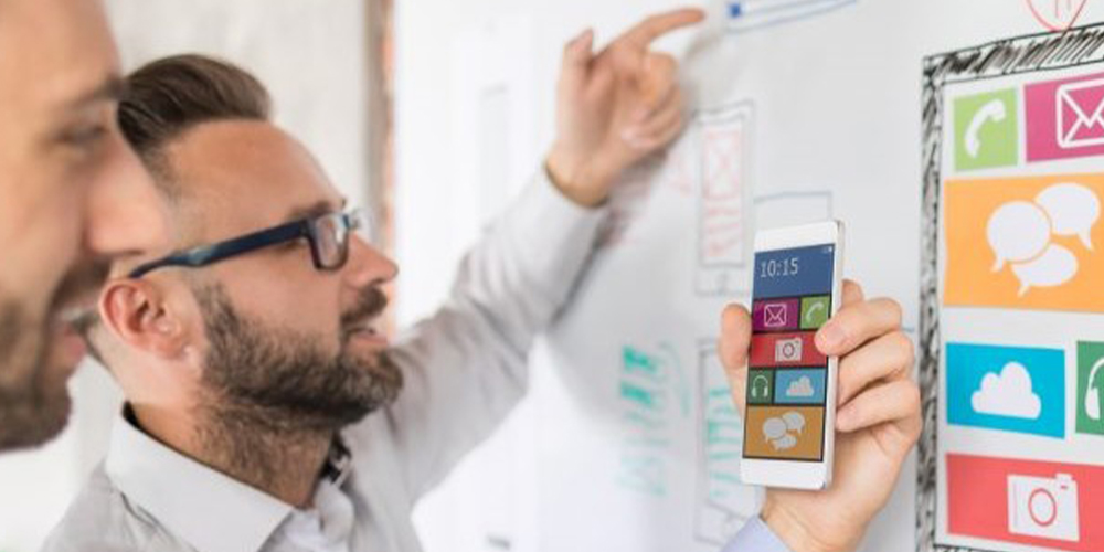men looking at whiteboard and phone
