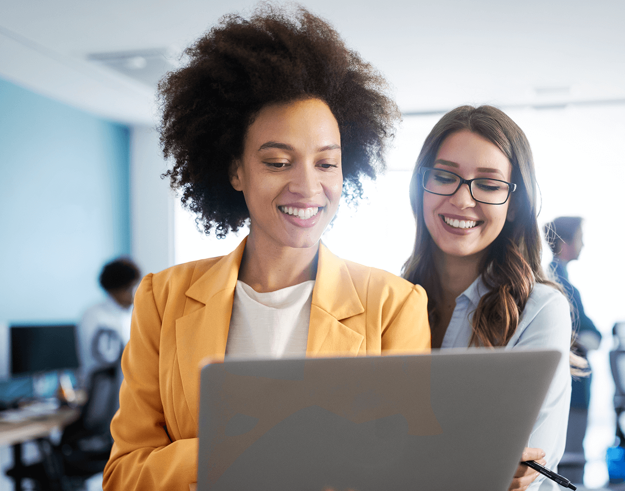 Two female coworkers smiling at laptop