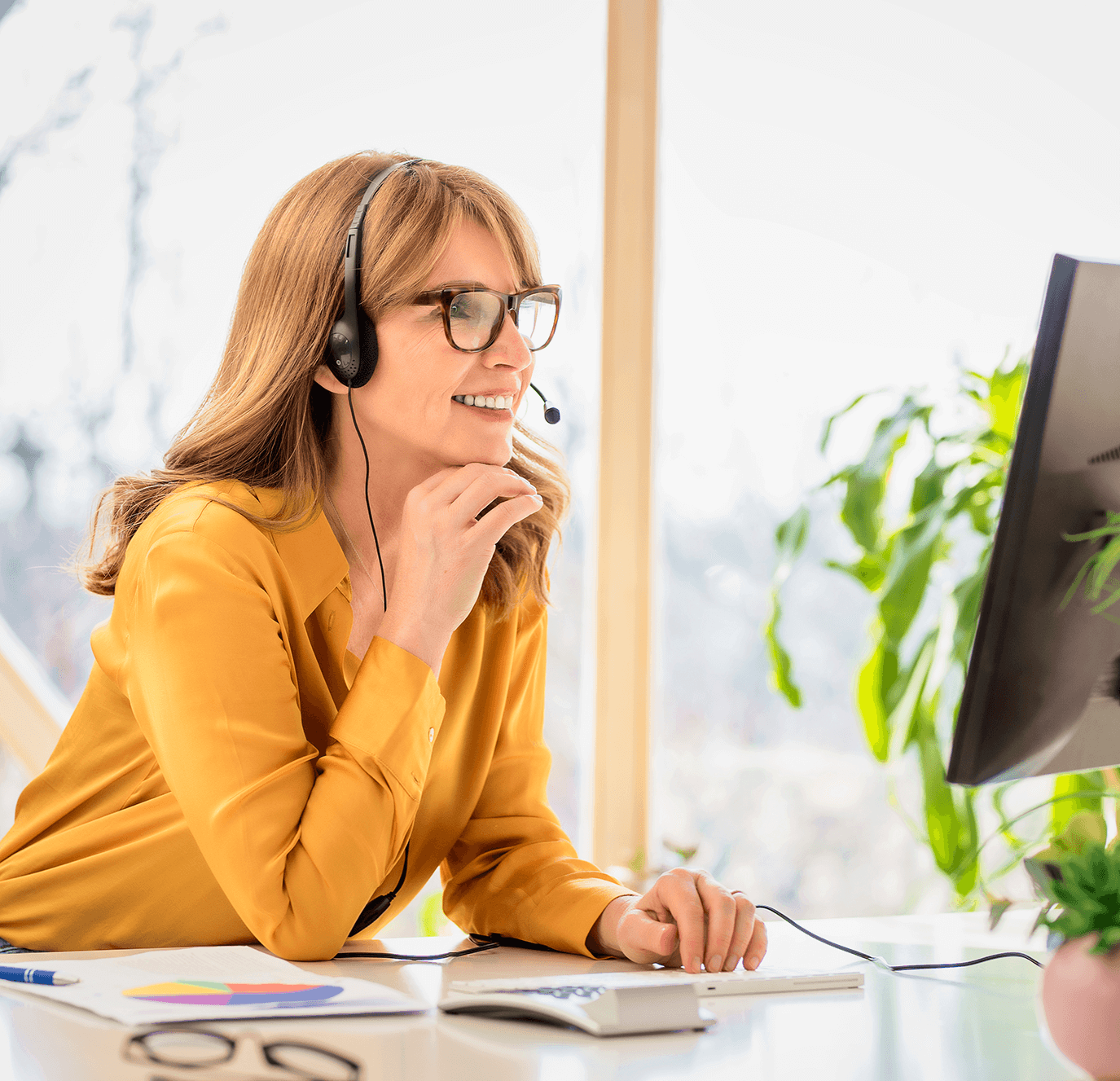 Smiling woman working on desktop answering call